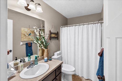 A Full Bathroom Serves the Additional Bedrooms Bathroom with white shower curtain.png