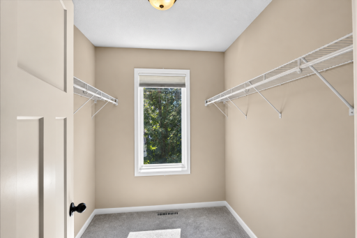 A Sunlit Walk-In Closet Offers Generous Storage Walk in closet primary bedroom.png