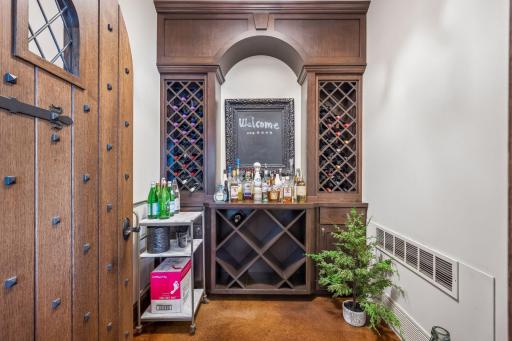 An arched doorway introduces the dedicated wine room, complete with built-in wine racks and climate-controlled settings designed for a thoughtfully curated collection.
