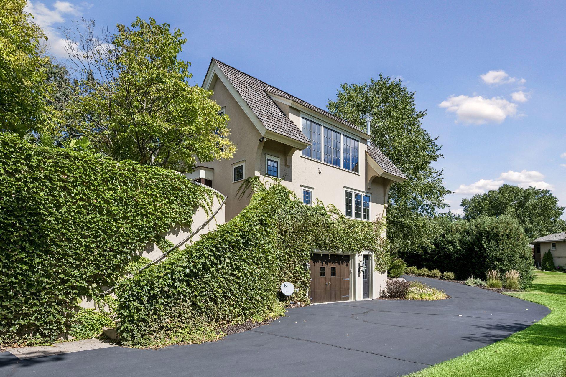 The expansive driveway continues beyond the detached garage, providing convenient access to the backyard and additional tuck-under garage spaces.