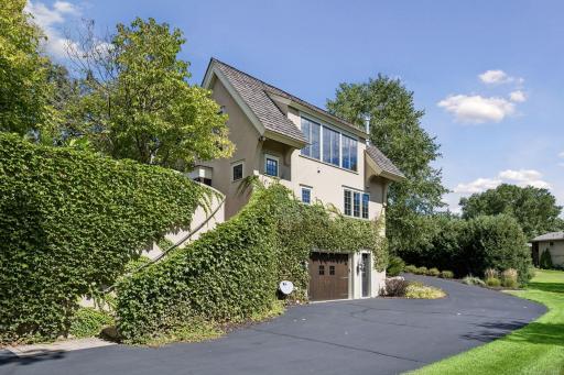 The expansive driveway continues beyond the detached garage, providing convenient access to the backyard and additional tuck-under garage spaces.