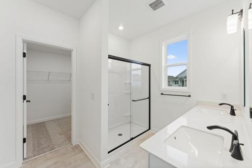 Featuring a dual-sink vanity, a glass-enclosed shower and direct access to the walk-in closet, the en-suite bathroom streamlines morning routines