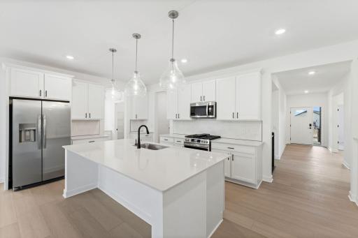 The kitchen features a fluid open-concept layout that is ideal for preparing meals, complemented by a multifunctional center island, plenty of cabinet space and quartz countertops.