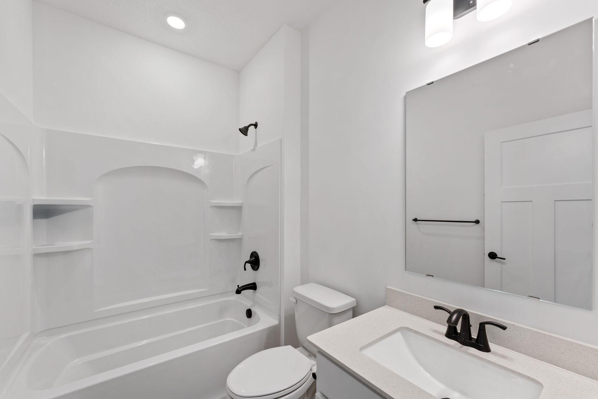 Conveniently located alongside the secondary bedroom, this full bathroom features an undermount sink with a Moen® faucet and a combination tub and shower with built-in shelves.
