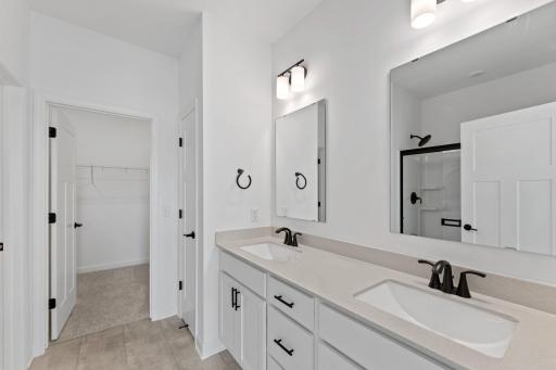 Quartz-topped dual undermount sinks with MoenÂ® faucets in the spa-inspired ownerâs suite bathroom