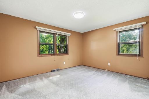 First upper level bedroom boasts two windows bringing natural light in while showcasing views of the surrounding greenery.