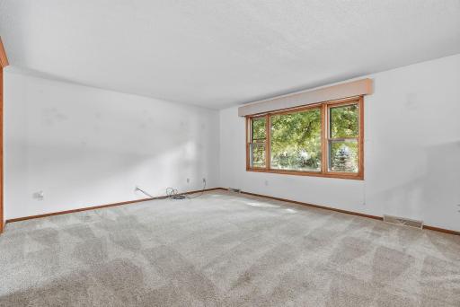 A large window fills the living room with natural light while offering a peaceful view of the tree-lined yard.