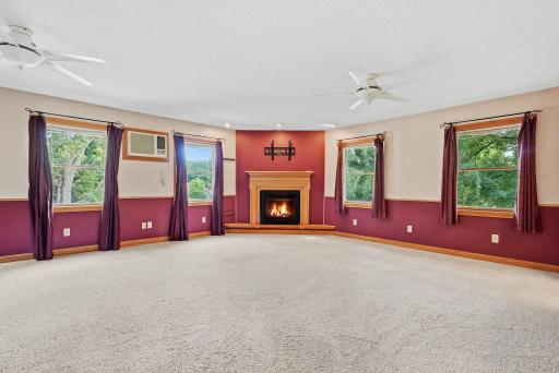 An impressively spacious primary bedroom features a fireplace and numerous windows.