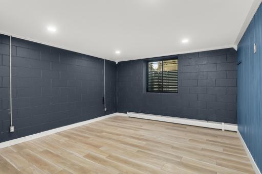 Finished basement flex room with recessed lights and egress window