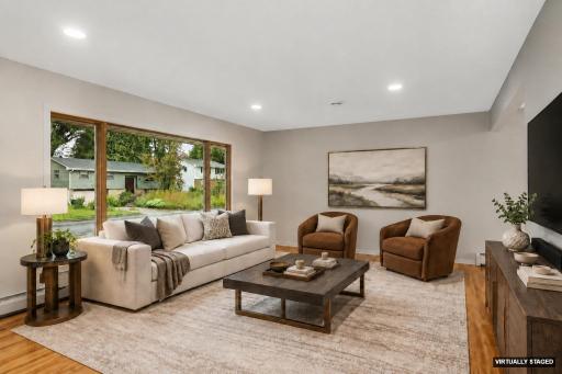 Main level living room with huge picture window & hardwood floors (virtually staged)