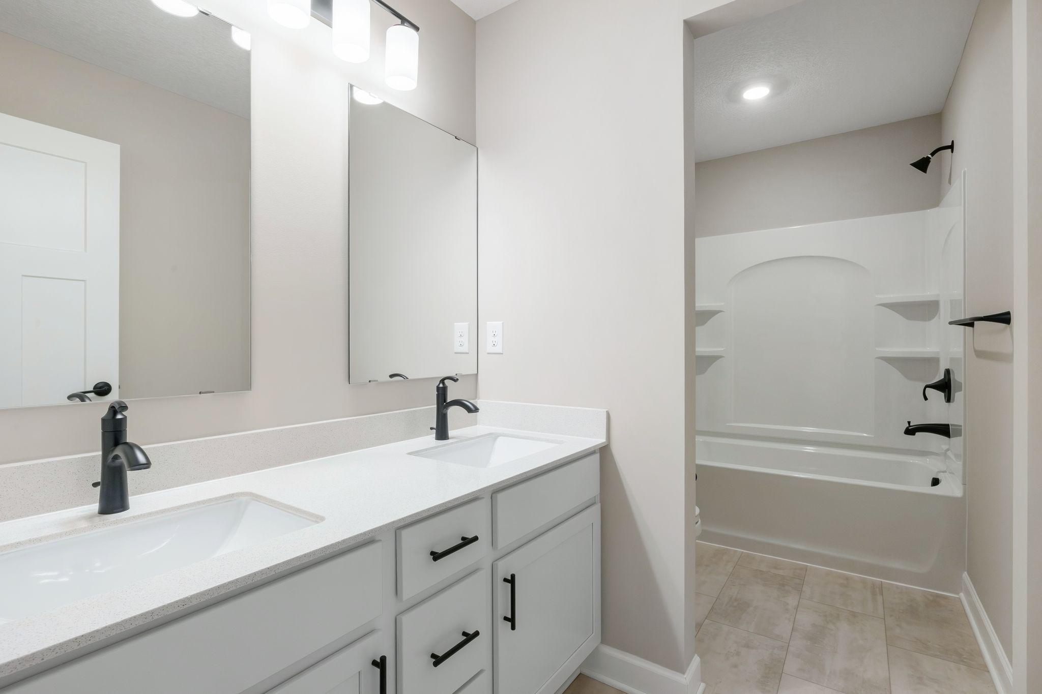 This full bathroom is conveniently located on the second floor and showcases dual sinks and a shower-tub combination.