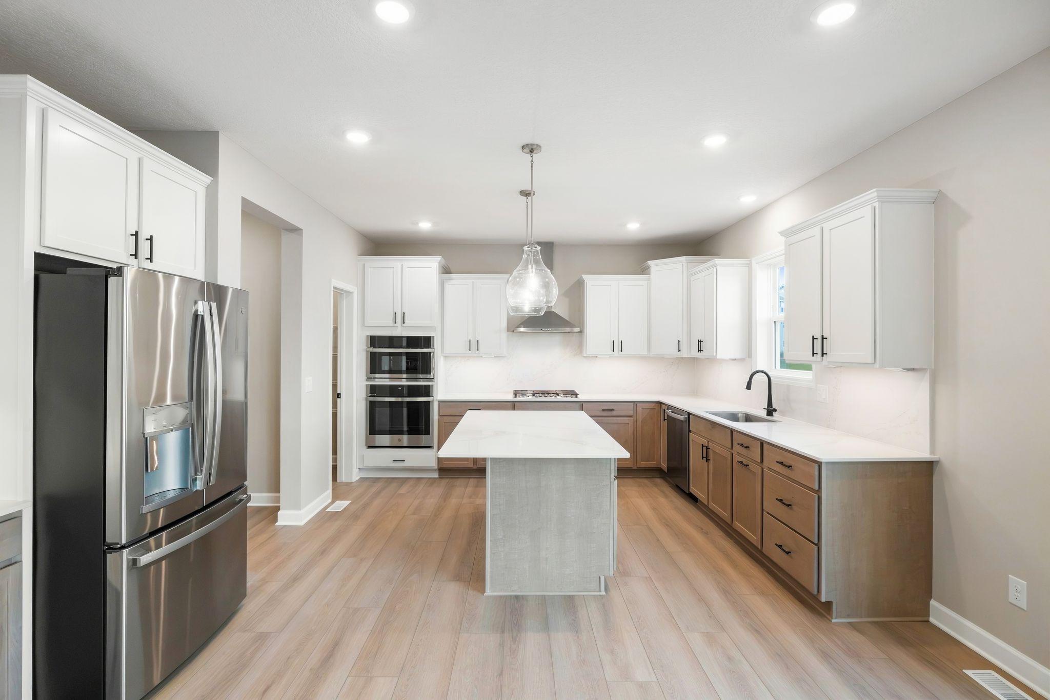 This stylish kitchen showcases a large center island, Shaker-style cabinetry, and brand-new stainless-steel appliances.