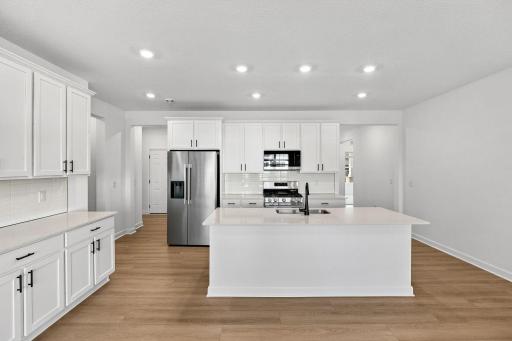 A galley-style kichen featuring brand-new stainless steel appliances, a center island that extends out to a breakfast bar and plenty of cabinetry storage.