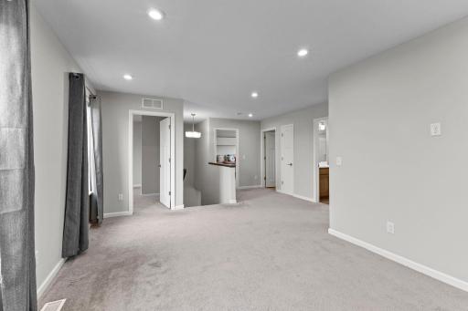 A spacious upper-level hallway connects all three bedrooms, the loft, laundry, and bathrooms, creating a functional and convenient layout.