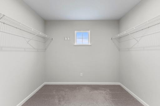 An oversized walk-in closet provides excellent storage with shelving and hanging space on both sides, plus a window for natural light.