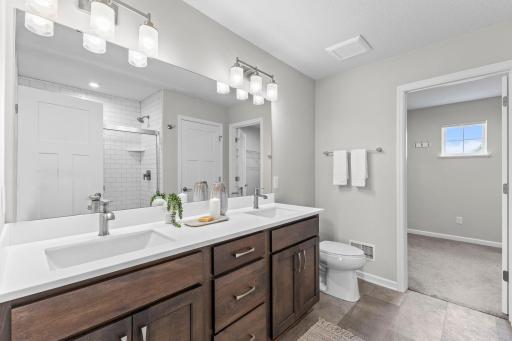 The private primary bathroom features a large double-sink quartz vanity, modern fixtures, and direct access to the walk-in closet.