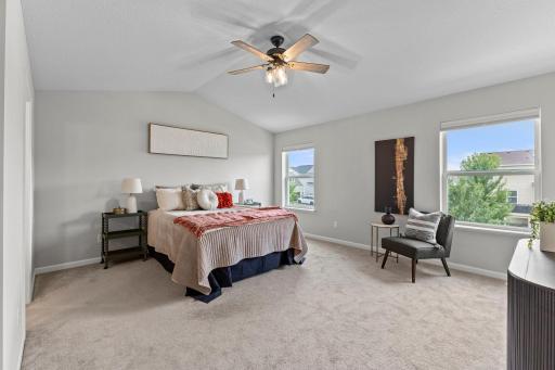 The spacious primary suite features a vaulted ceiling, ceiling fan, multiple windows, and plenty of room for a king bedroom set.