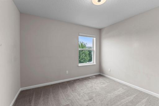 A comfortable secondary bedroom with a large window and plenty of space for a bed, dresser, and additional furniture.