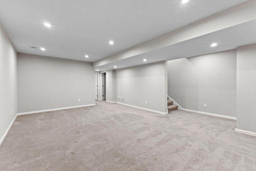 Another view shows just how spacious this finished lower level is. Recessed lighting, neutral finishes, and plenty of open floor space make it easy to customize for your needs.