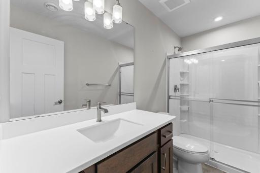 Convenient lower-level bathroom featuring a large vanity and walk-in shower with glass doors.