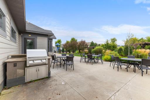 Spacious outdoor patio with built-in grilling area, plenty of seating, and beautifully landscaped surroundings for gathering and entertaining.