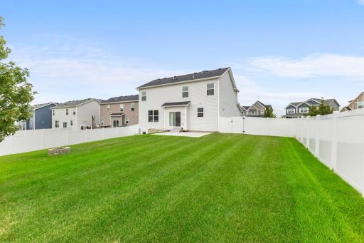 The spacious backyard is fully enclosed with a white privacy fence and offers plenty of usable lawn space for outdoor activities, pets, or entertaining.