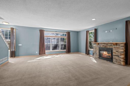 The living room is anchored by a gas fireplace with a stone surround and wide mantel, creating an inviting spot to settle in.