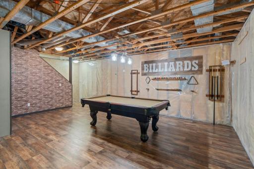 A spacious family room with updated laminate flooring (2021), statement lighting, and a pool table creates a fun place to hang out.