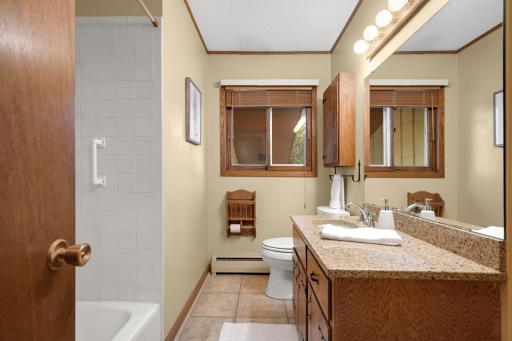 Full bath with a long vanity, tiled floor and tub/shower.