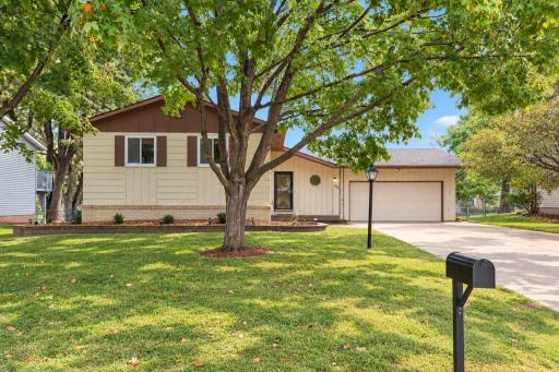 A welcoming front yard with mature shade trees and an attached 2-car garage.