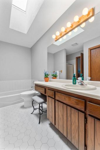 The bathroom features neutral tile flooring, a tiled tub surround, and an oversized vanity with plenty of space to get ready for the day.