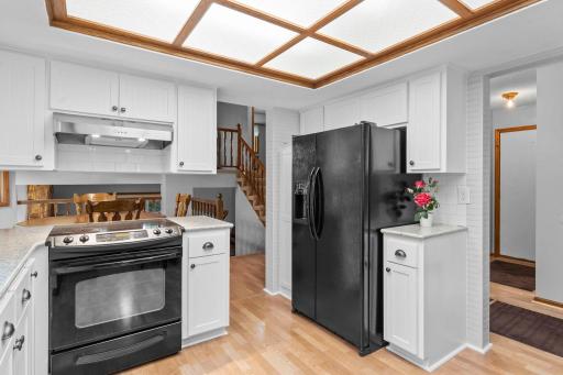 Modern kitchen features newer countertops, subway tiled backsplash, white cabinetry, stylish fixtures, and wainscoting accents.
