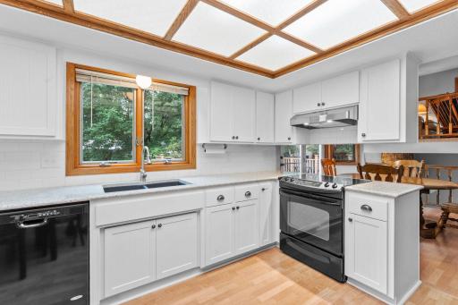 The updated kitchen features newer countertops, subway tiled backsplash, white cabinetry, stylish fixtures, and wainscoting accents, with the added convenience of main-level laundry nearby.