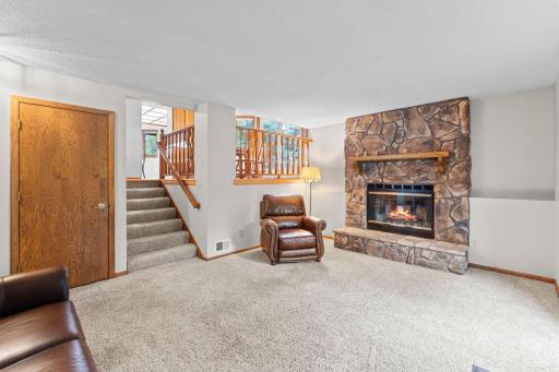 The lower level is highlighted by a cozy stone wood-burning fireplace, flexible living space, and direct walkout to the backyard.