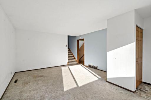 The living room opens to the stairs, leading up to the bedrooms and down to the lower level.