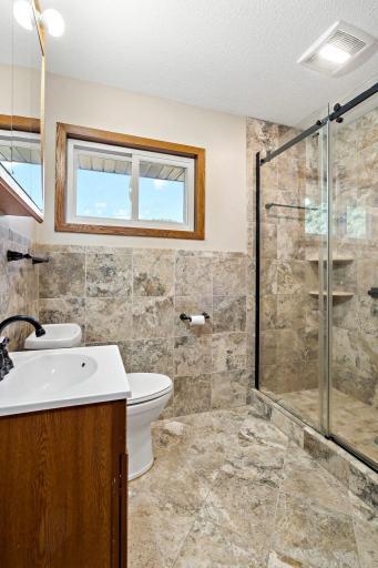 The spa-inspired bath features floor-to-ceiling tile and a glass-door walk-in shower.