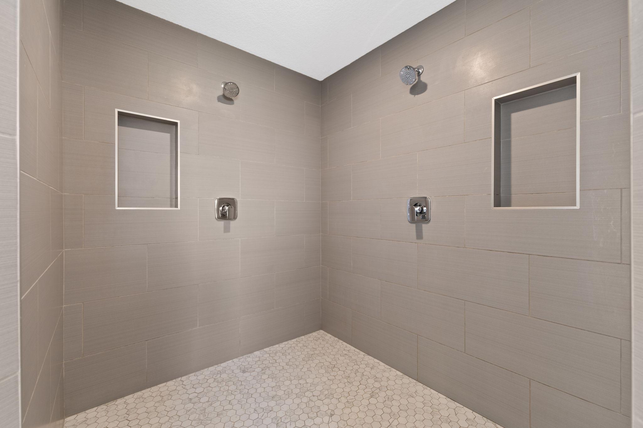 The impressive walk-in shower features dual shower fixtures and custom tile from floor to ceiling.