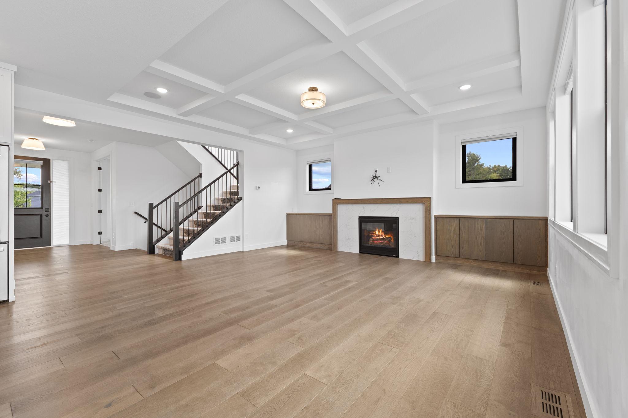 The living room features beautiful custom millwork, wood flooring and a coffered ceiling overhead.