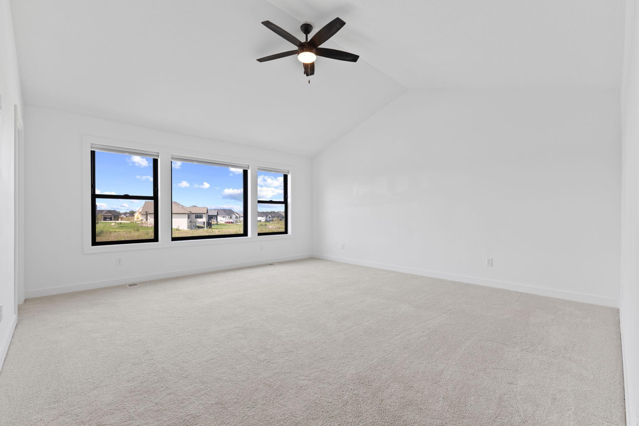 Vaulted ceilings and multiple windows make the primary bedroom feel especially open and airy.