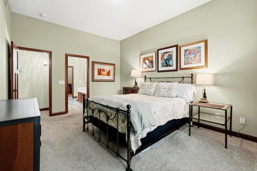 This cozy primary bedroom features soft green walls, warm lighting from lamps, and a welcoming retreat feel.