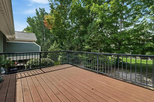This charming home features a well-maintained deck with sleek railings, complemented by large windows and a cozy interior visible through the glass.