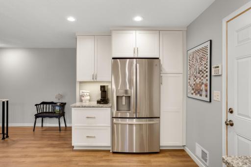 Thoughtful cabinetry surrounds the refrigerator, providing additional storage and a convenient beverage or coffee station.