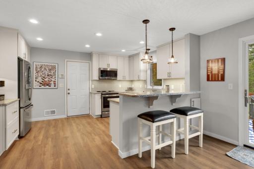 Updated kitchen features white cabinetry, granite countertops, stainless steel appliances and breakfast-bar seating.