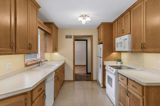 Classic galley kitchen with warm wood cabinetry, ample prep space, abundant storage, and natural light. Functional design with everything within easy reach.