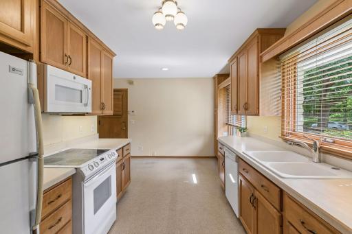 The galley kitchen flows seamlessly into the informal dining area, offering an efficient layout with ample cabinetry, generous counter space, and a bright, welcoming atmosphere.
