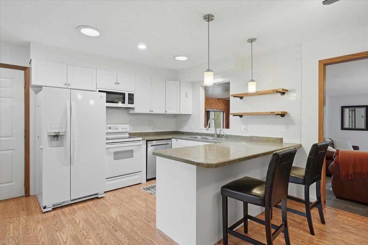 Bright and crisp kitchen featuring white cabinetry, lots of counter space and a breakfast bar.
