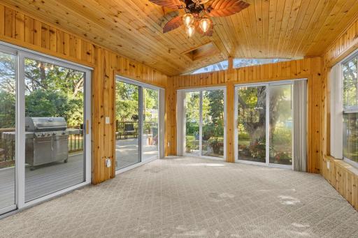 Bright and inviting porch with large windows, four sliding glass doors, and direct access to the maintenance-free deck from multiple sides