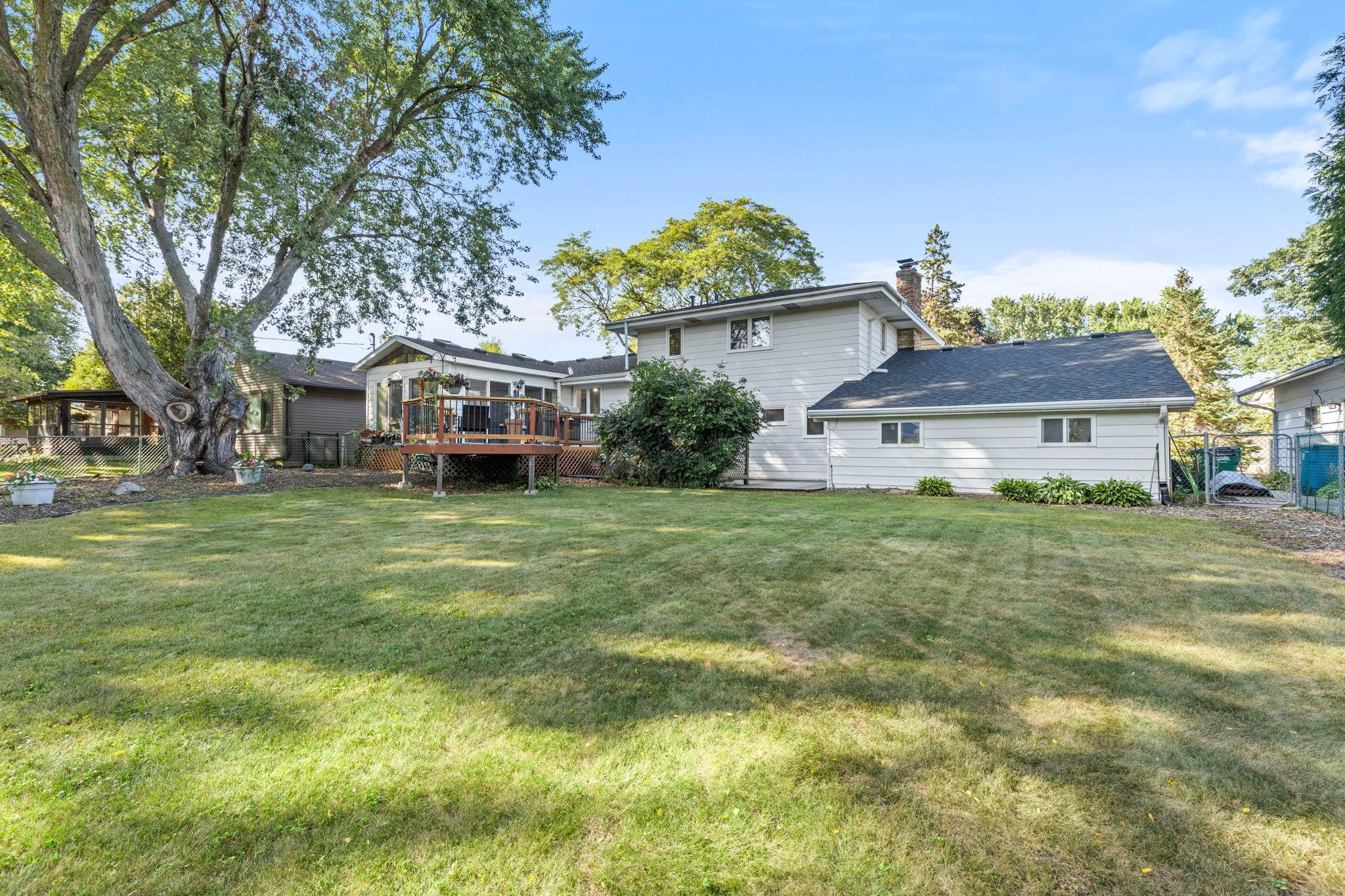 A large, flat yard with mature landscaping creates a welcoming outdoor space for every season