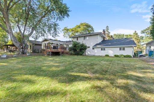 A large, flat yard with mature landscaping creates a welcoming outdoor space for every season