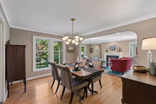 Formal Dining Room - Hardwood floors and large windows define the spacious formal dining room, with a wide arched opening creating an open connection to the adjoining living room.